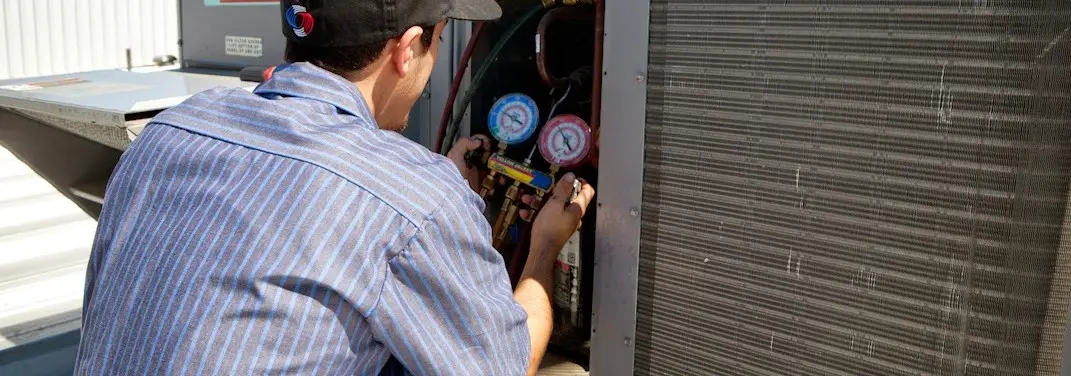 HVAC technician servicing a condenser unit in Vincennes